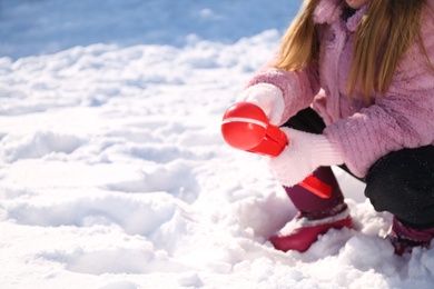 Photo of Little girl playing with snowball maker outdoors, closeup