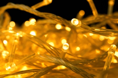 Glowing Christmas lights on yellow background, closeup