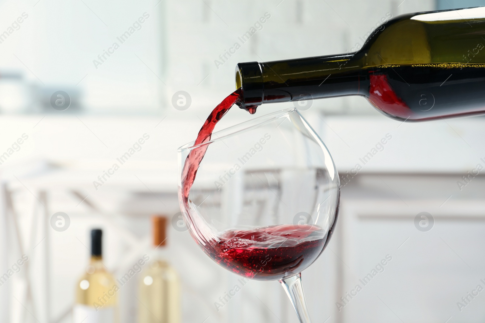 Photo of Pouring delicious red wine into glass on light background