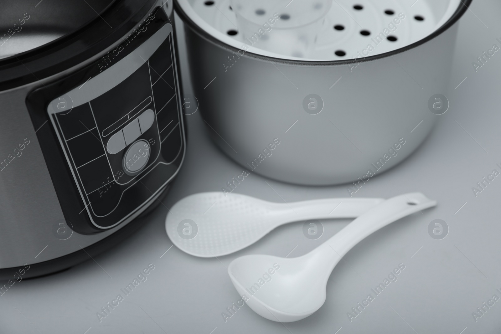 Photo of Modern electric multi cooker, parts and accessories on grey background, closeup