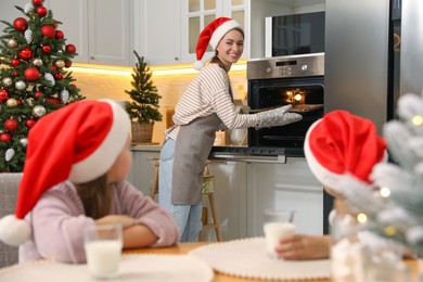 Mother with her cute little children making Christmas cookies in kitchen