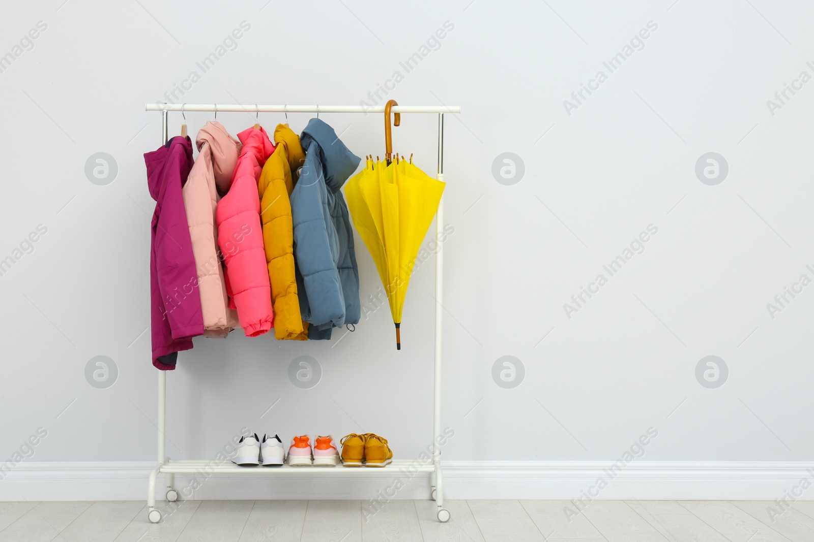 Photo of Rack with warm jackets in room. Space for text