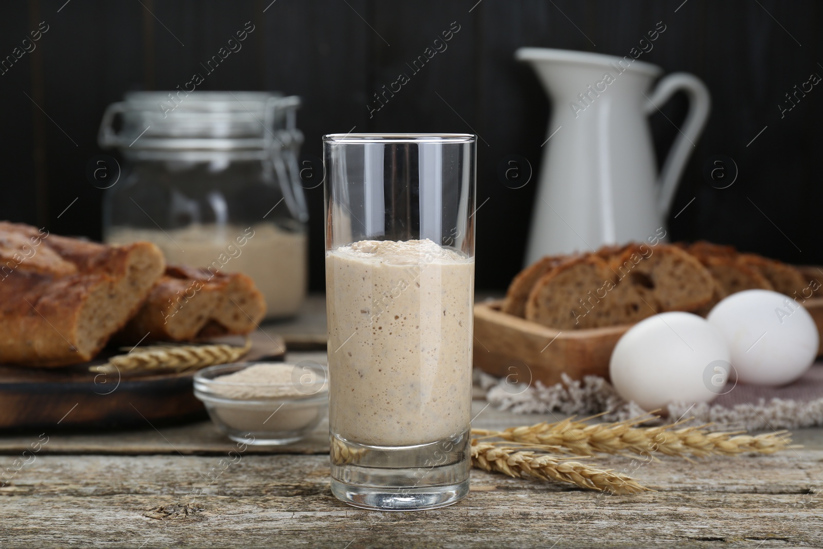 Photo of Glass with fresh sourdough on wooden table