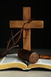 Photo of Judge gavel, bible, wooden cross and crown of thorns on grey table