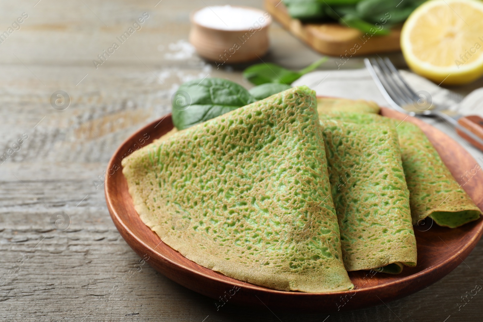 Photo of Delicious spinach crepes served on wooden table