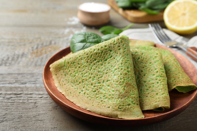 Delicious spinach crepes served on wooden table