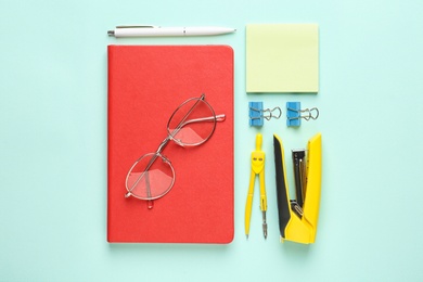 Flat lay composition with red notebook and office stationery on light blue background