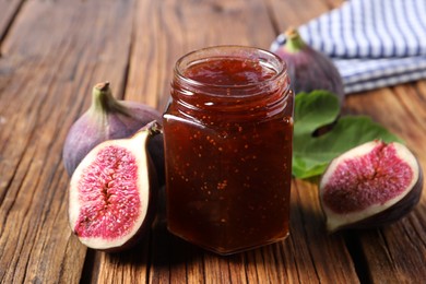 Photo of Jar of tasty sweet jam and fresh figs on wooden table, closeup