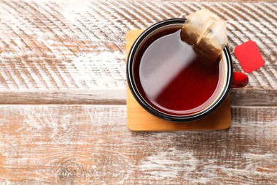 Tea bag in cup with hot drink on wooden rustic table, top view. Space for text