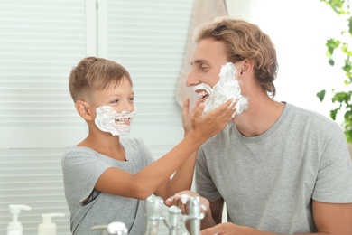 Father and son applying shaving foam in bathroom