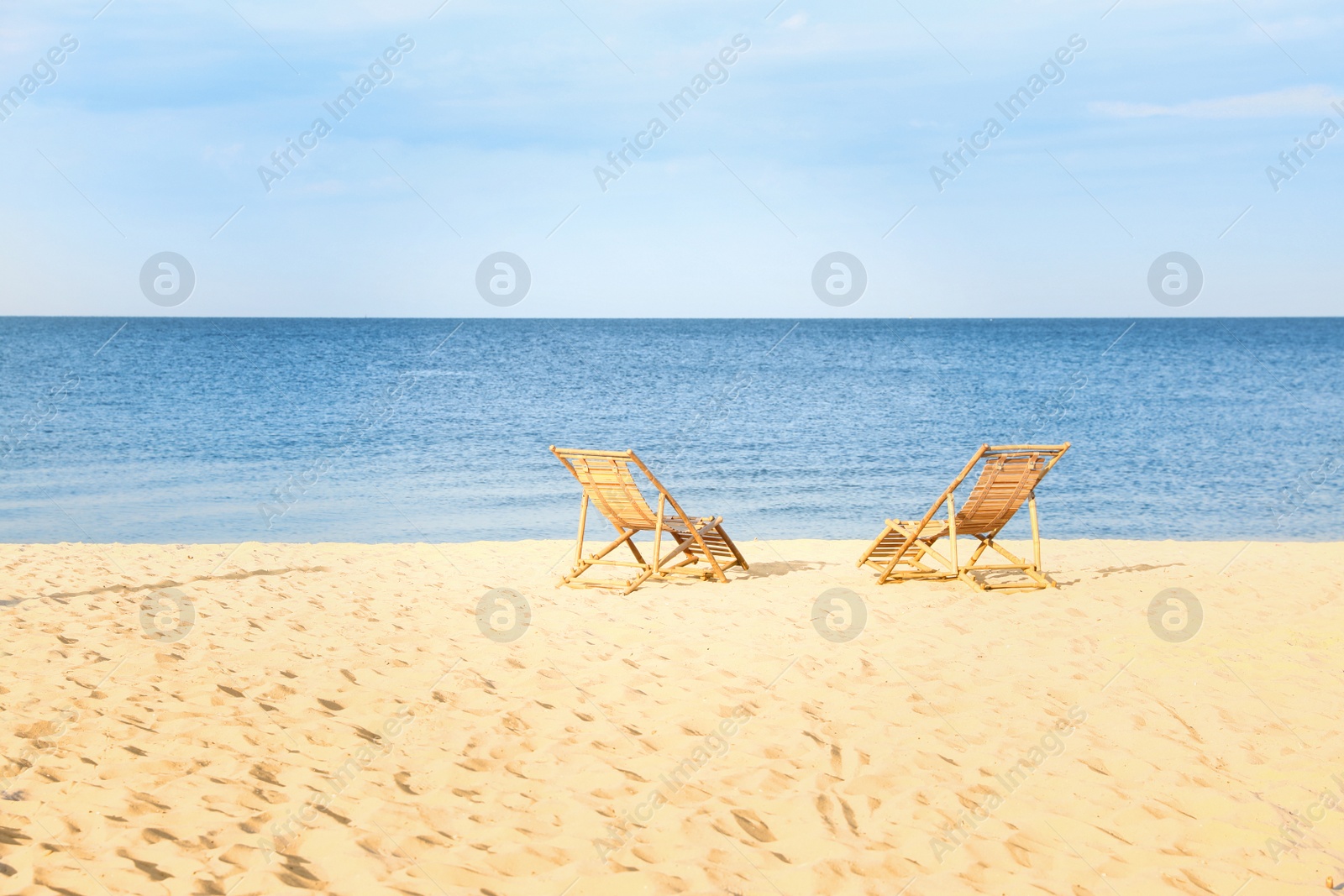 Photo of Sandy beach with empty wooden sunbeds on sunny day