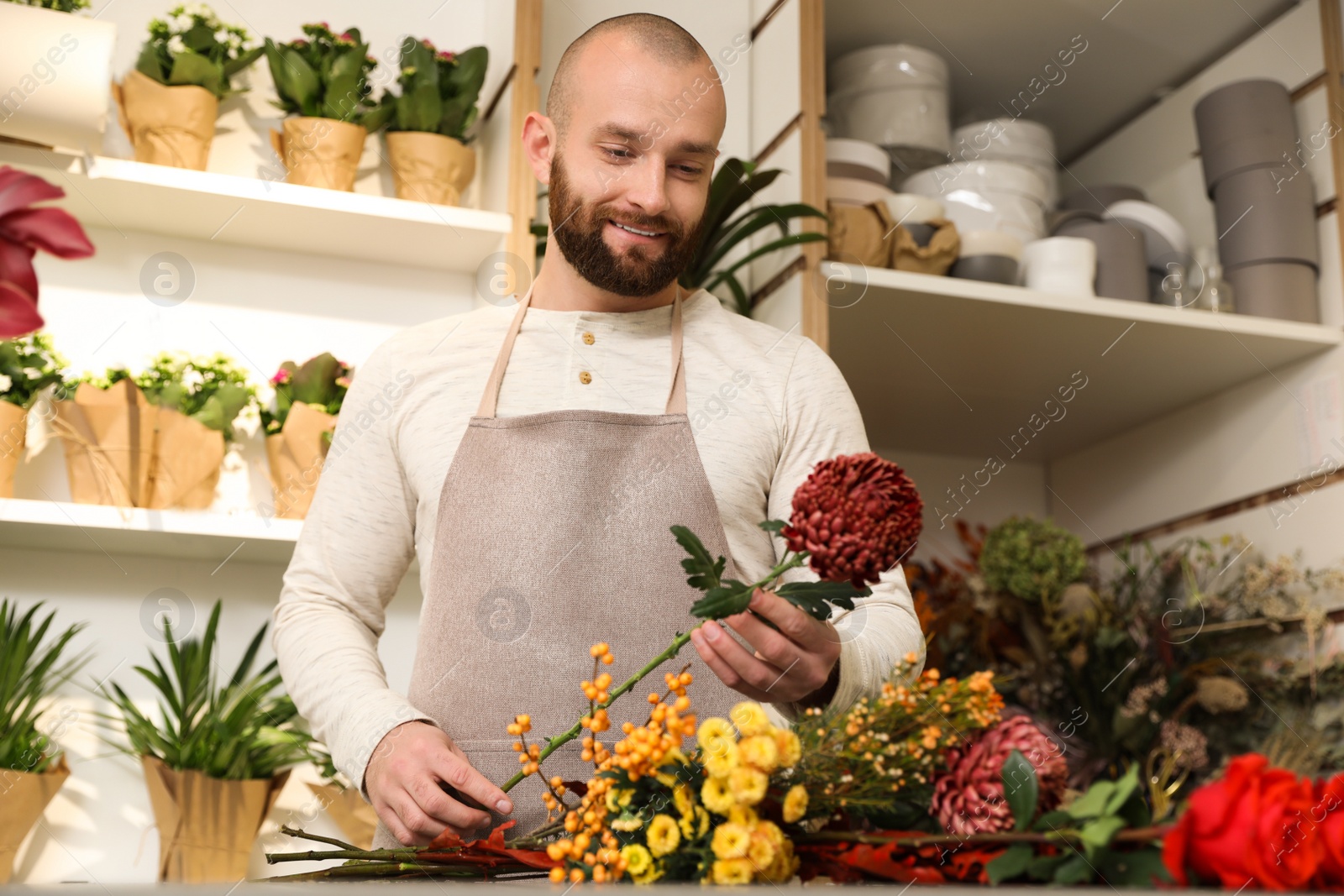 Photo of Florist making bouquet with fresh flowers at table in shop