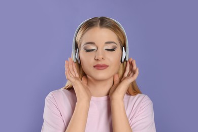 Photo of Beautiful woman in headphones enjoying music on violet background