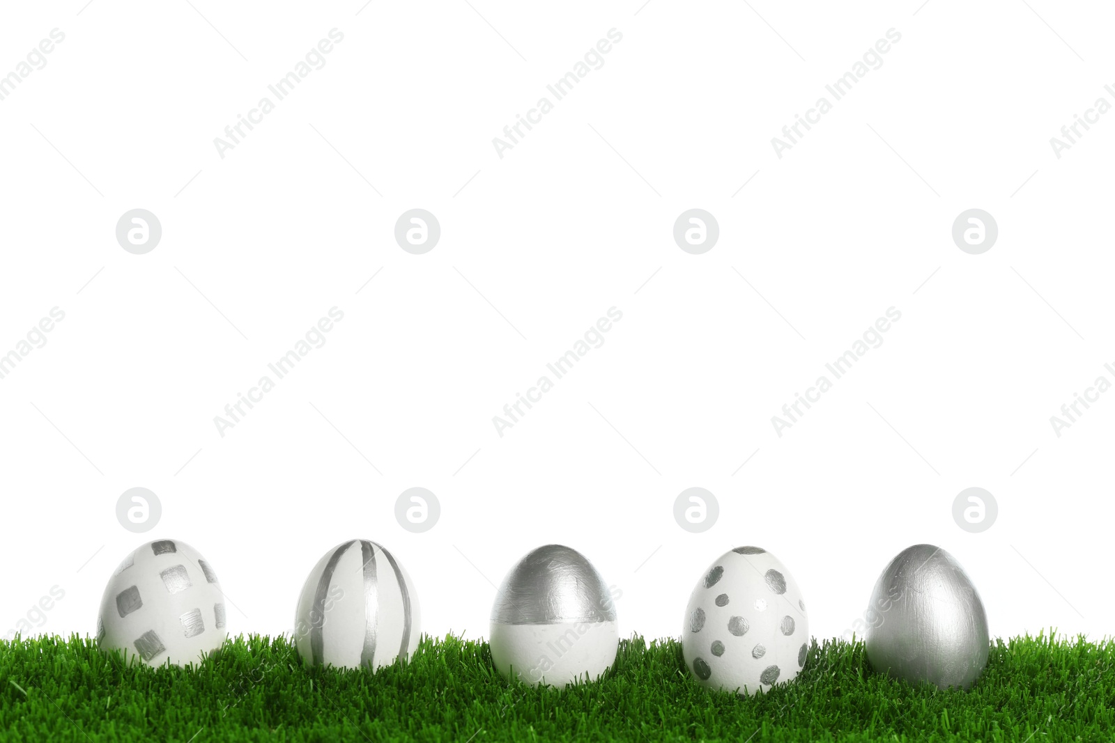 Photo of Line of painted Easter eggs on green lawn against white background