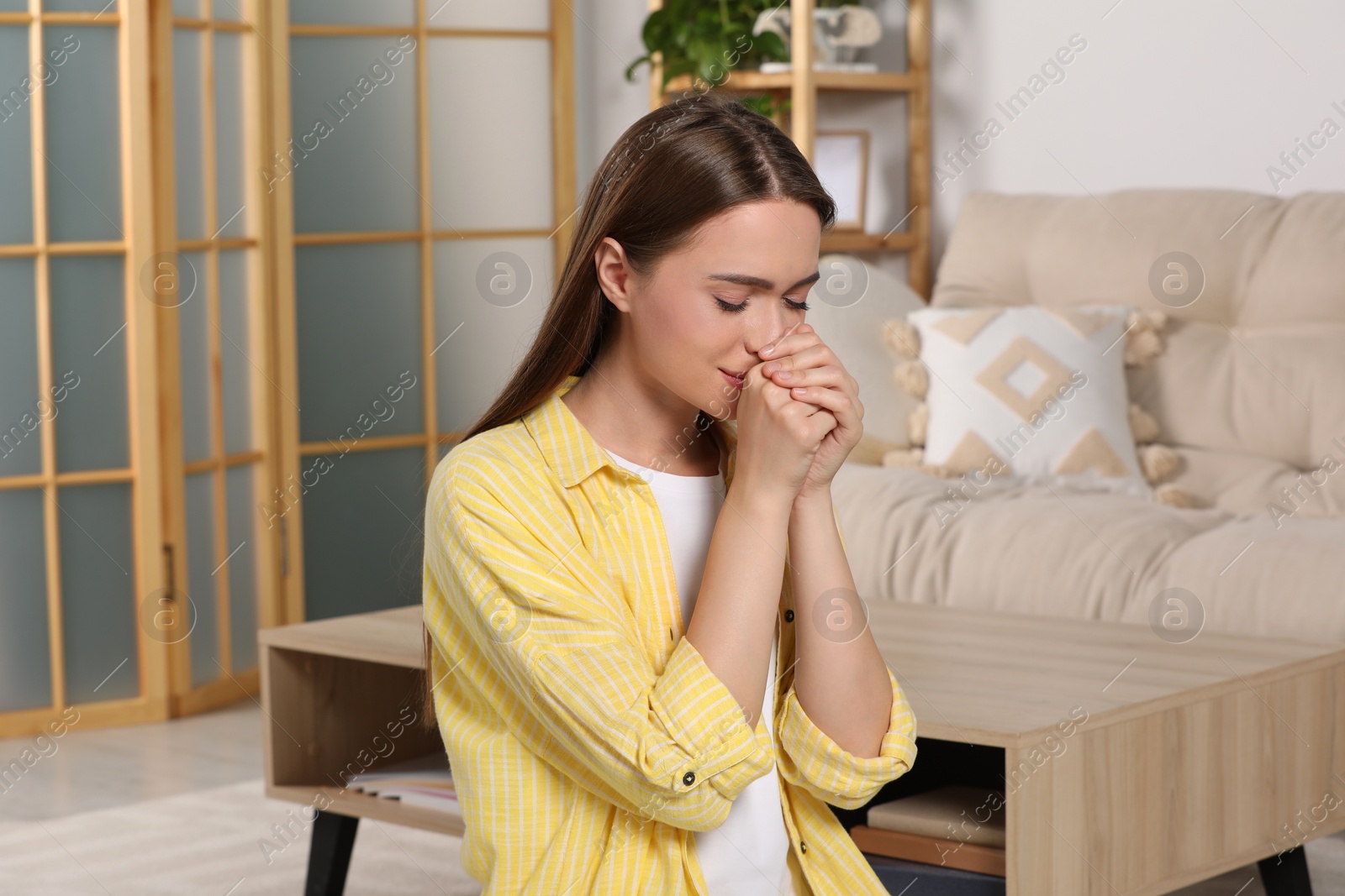 Photo of Woman with clasped hands praying at home