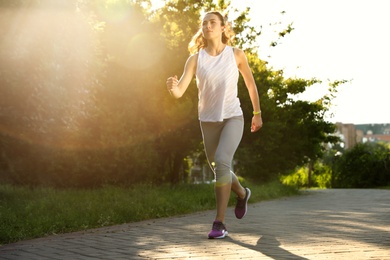 Photo of Young woman running in park on sunny day, space for text