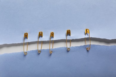Photo of Pieces of paper sheets joined with safety pins on white background, top view