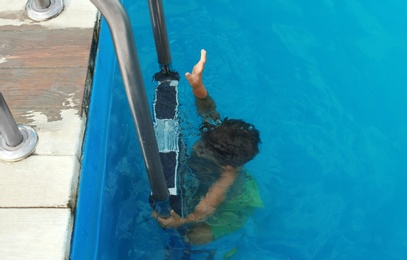 Photo of Little child under water in outdoor swimming pool. Dangerous situation