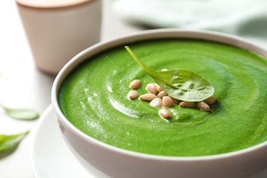 Photo of Bowl of healthy green soup with fresh spinach on table, closeup view