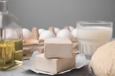 Photo of Blocks of compressed yeast and ingredients on white marble table, closeup