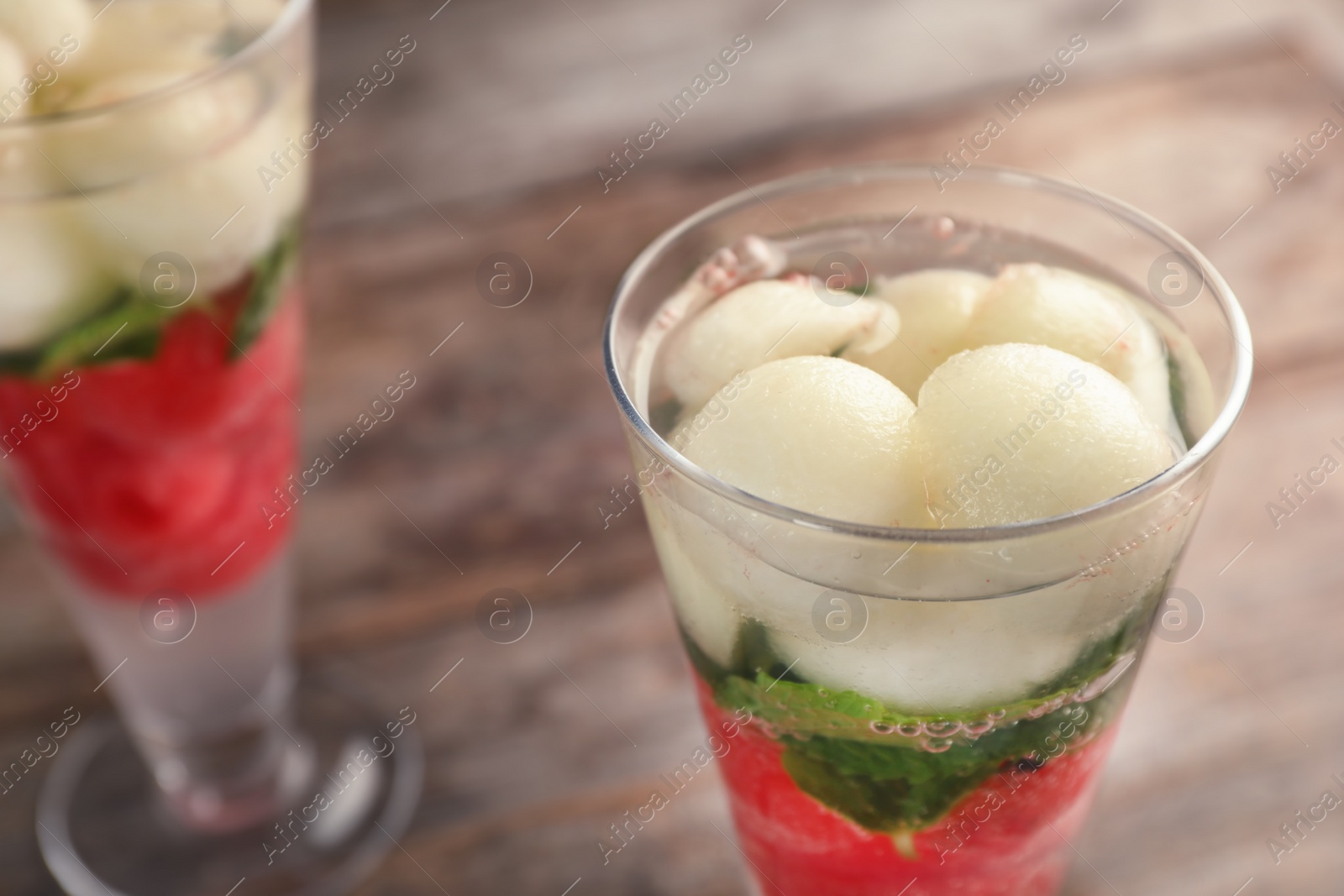 Photo of Glass with tasty melon and watermelon ball drink on wooden table, closeup