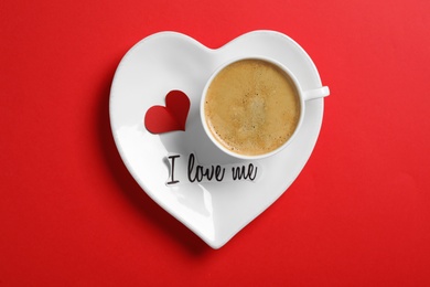 Paper with phrase I Love Me and cup of coffee on red background, top view