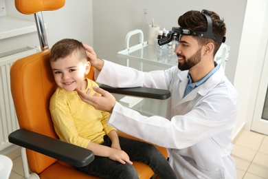 Photo of Professional otolaryngologist examining little boy in clinic. Hearing disorder