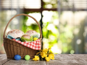 Image of Delicious Easter cakes and painted eggs on wooden table indoors. Space for text