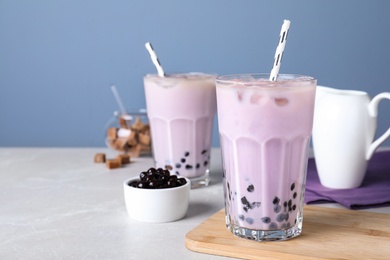 Photo of Bubble milk tea with tapioca balls on table against blue background. Space for text