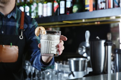 Photo of Barman holding White Russian cocktail in night club, closeup. Space for text