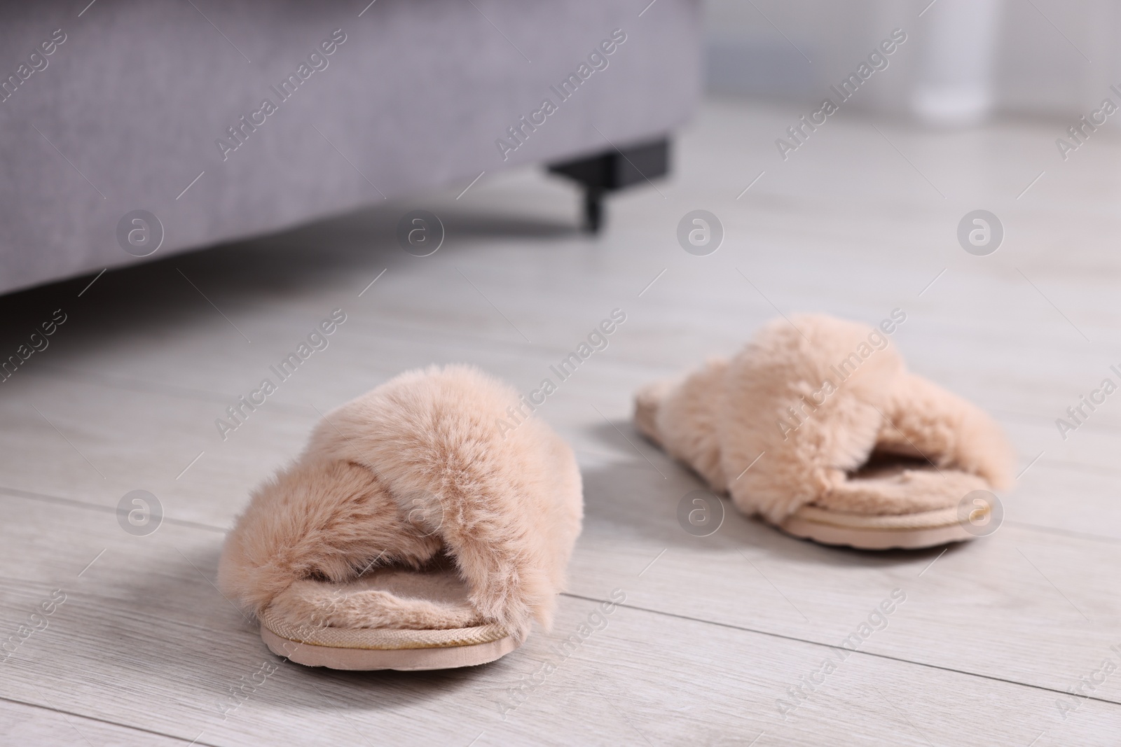 Photo of Beige soft slippers on light wooden floor at home