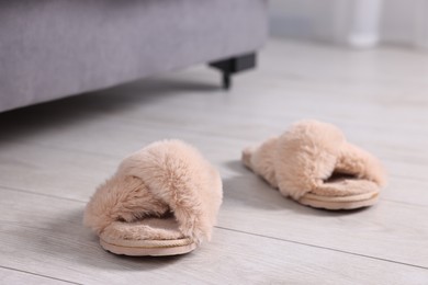 Beige soft slippers on light wooden floor at home