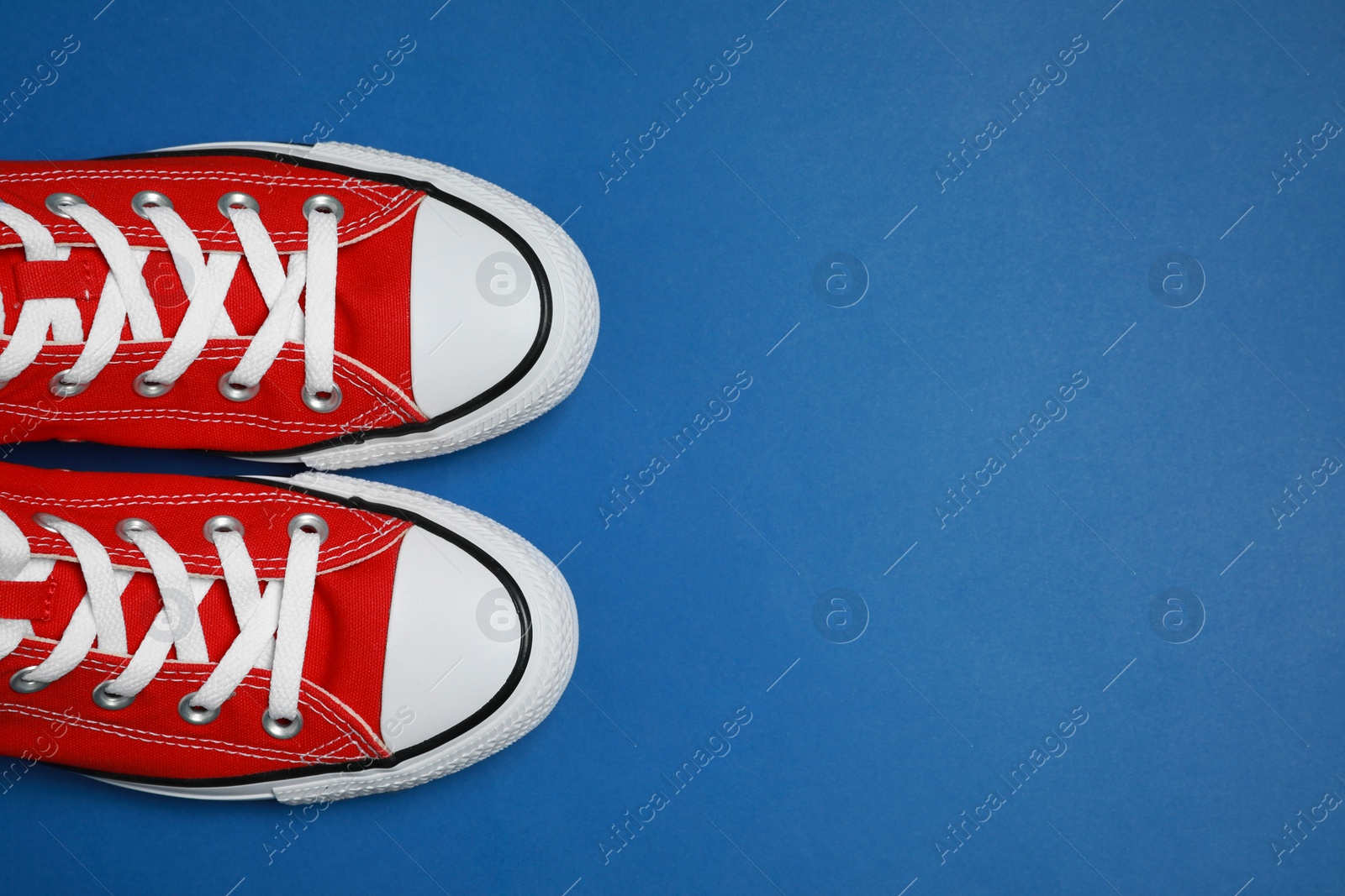 Photo of Pair of new stylish red sneakers on blue background, flat lay. Space for text