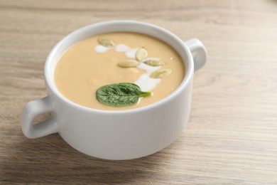 Photo of Healthy cream soup high in vegetable fats on wooden table, closeup