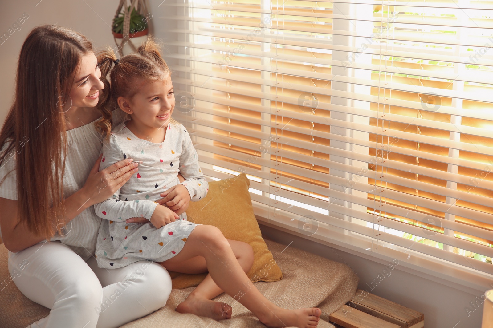 Photo of Happy mother with little daughter near window at home