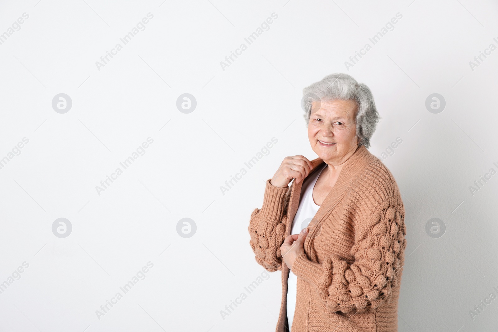 Photo of Portrait of grandmother in stylish clothes on light background, space for text