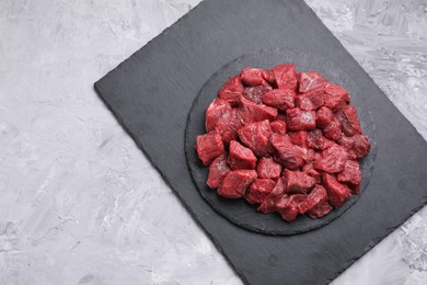 Pieces of raw beef meat on grey textured table, top view. Space for text