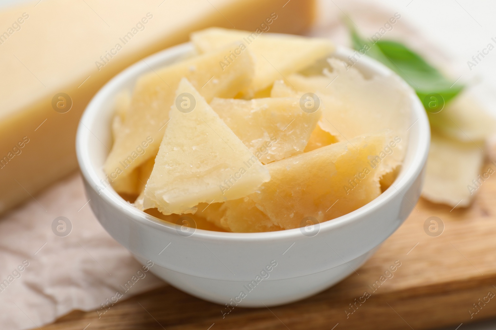 Photo of Bowl with parmesan cheese pieces on table, closeup