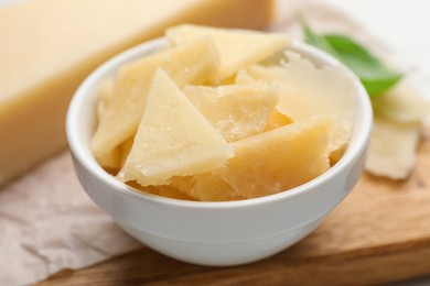 Bowl with parmesan cheese pieces on table, closeup