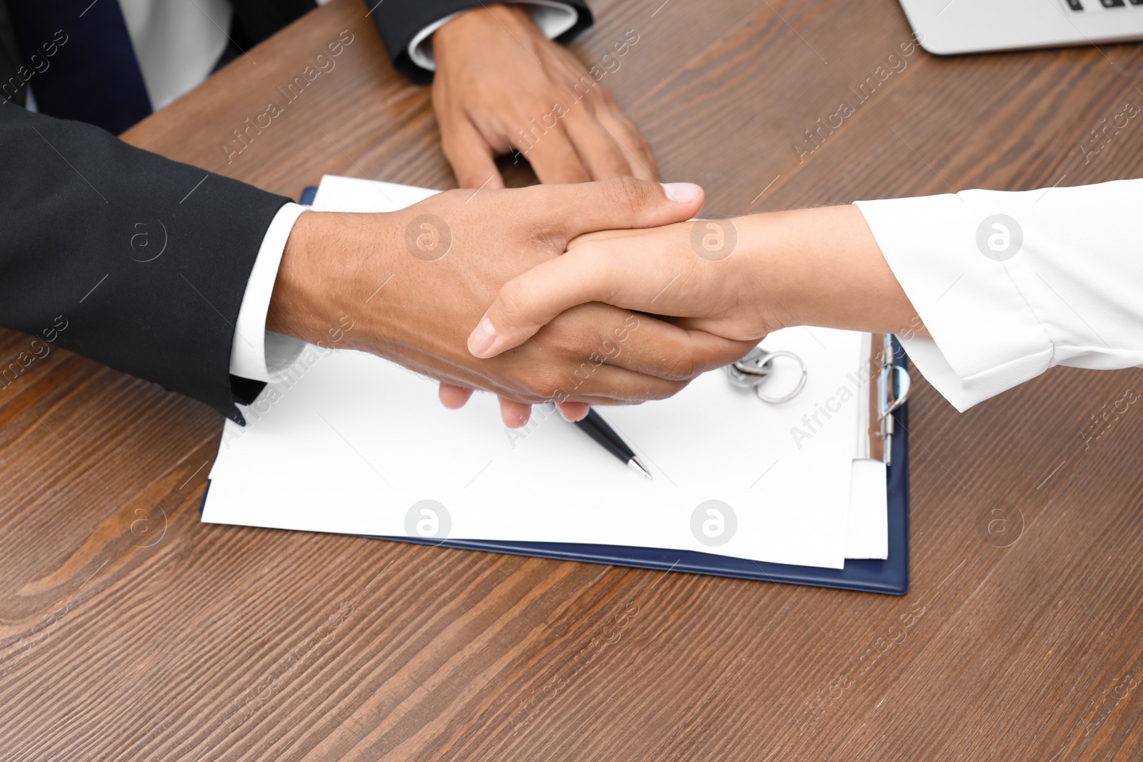 Photo of Woman shaking hands with real estate agent on meeting over table