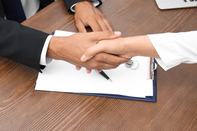 Woman shaking hands with real estate agent on meeting over table