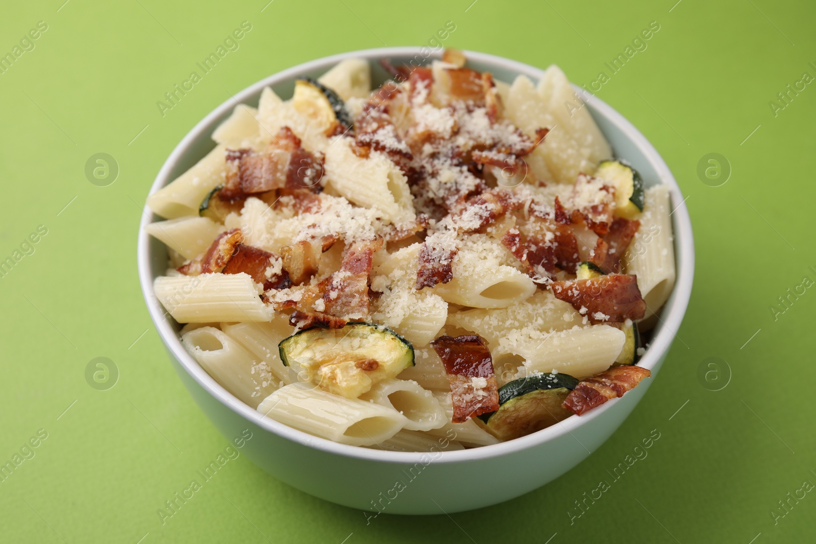 Photo of Tasty pasta with bacon and cheese on light green table, closeup