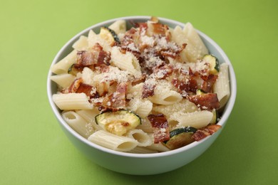 Tasty pasta with bacon and cheese on light green table, closeup