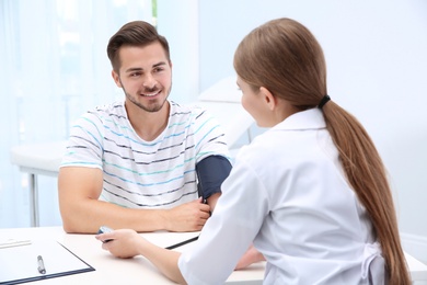 Photo of Doctor checking young man's pulse in hospital