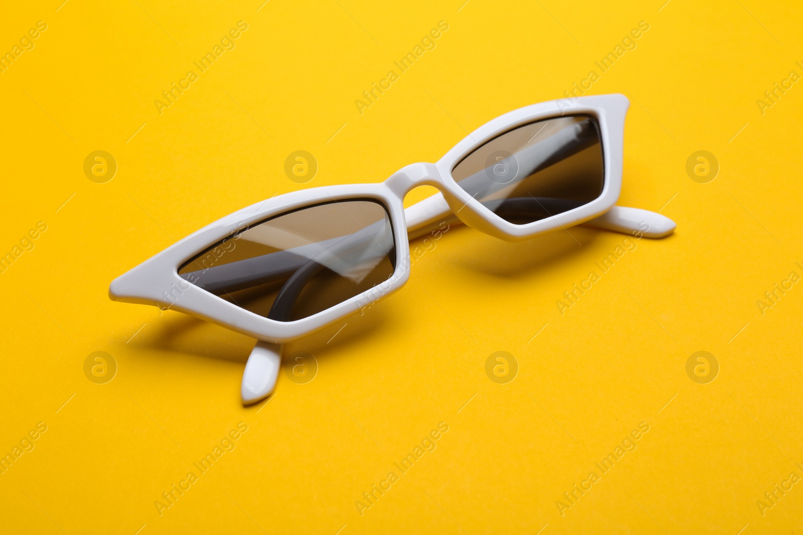 Photo of Stylish sunglasses on yellow background. Fashionable accessory