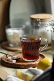 Photo of Glass cup with delicious tea and sugar on table