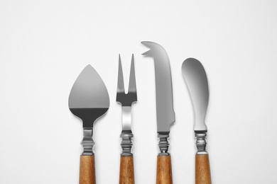 Cheese knives and fork on white background, top view