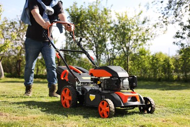 Man cutting green grass with lawn mower in garden, closeup