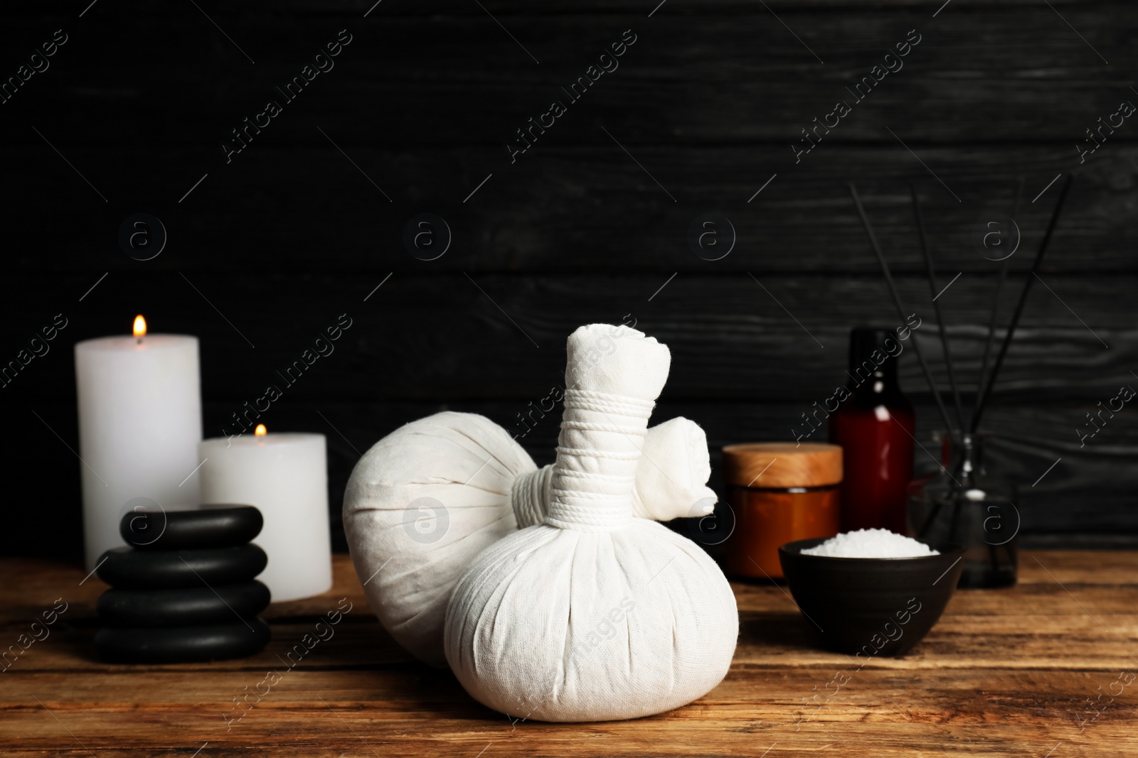 Photo of Herbal massage bags and other spa products on wooden table