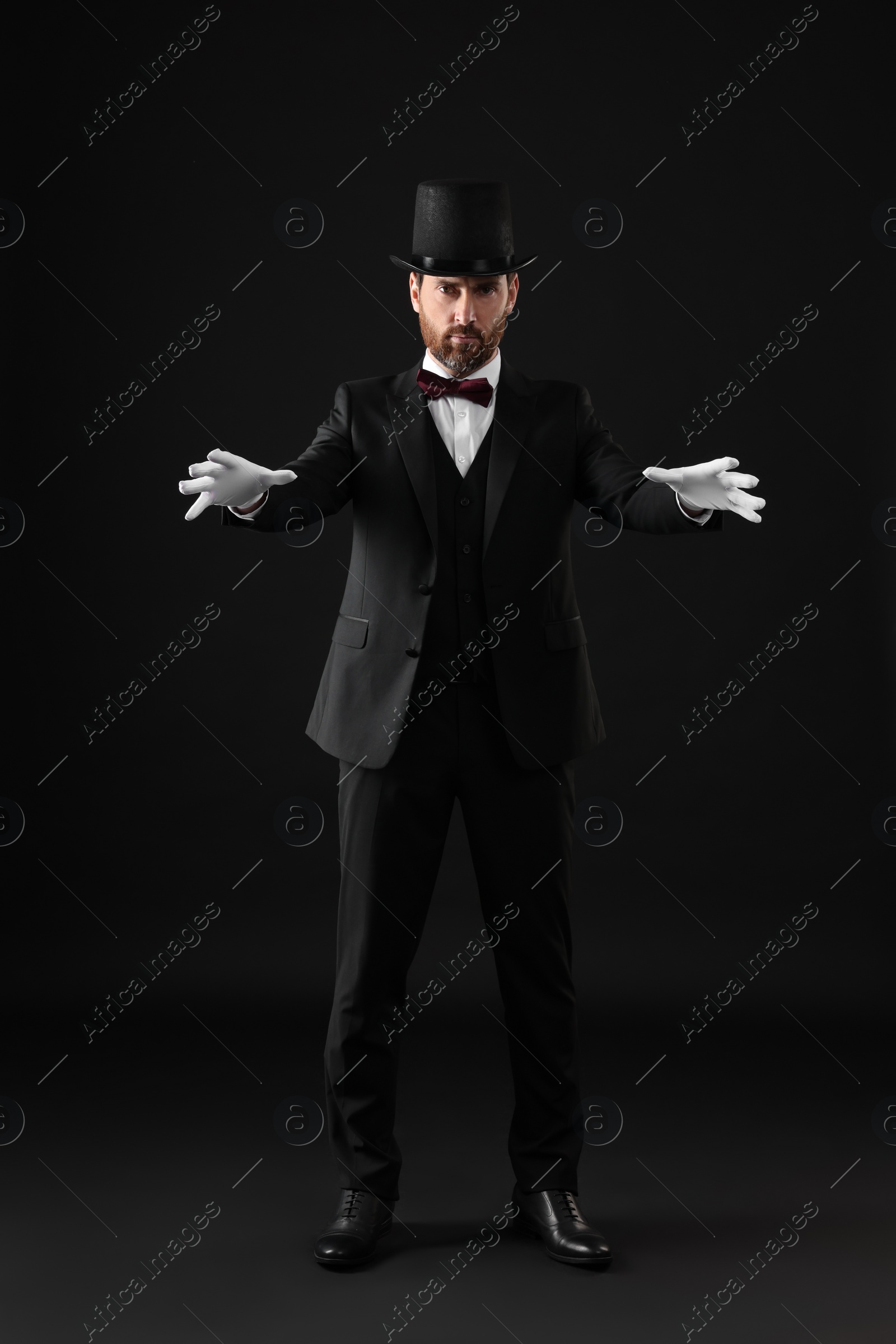 Photo of Magician in top hat on black background